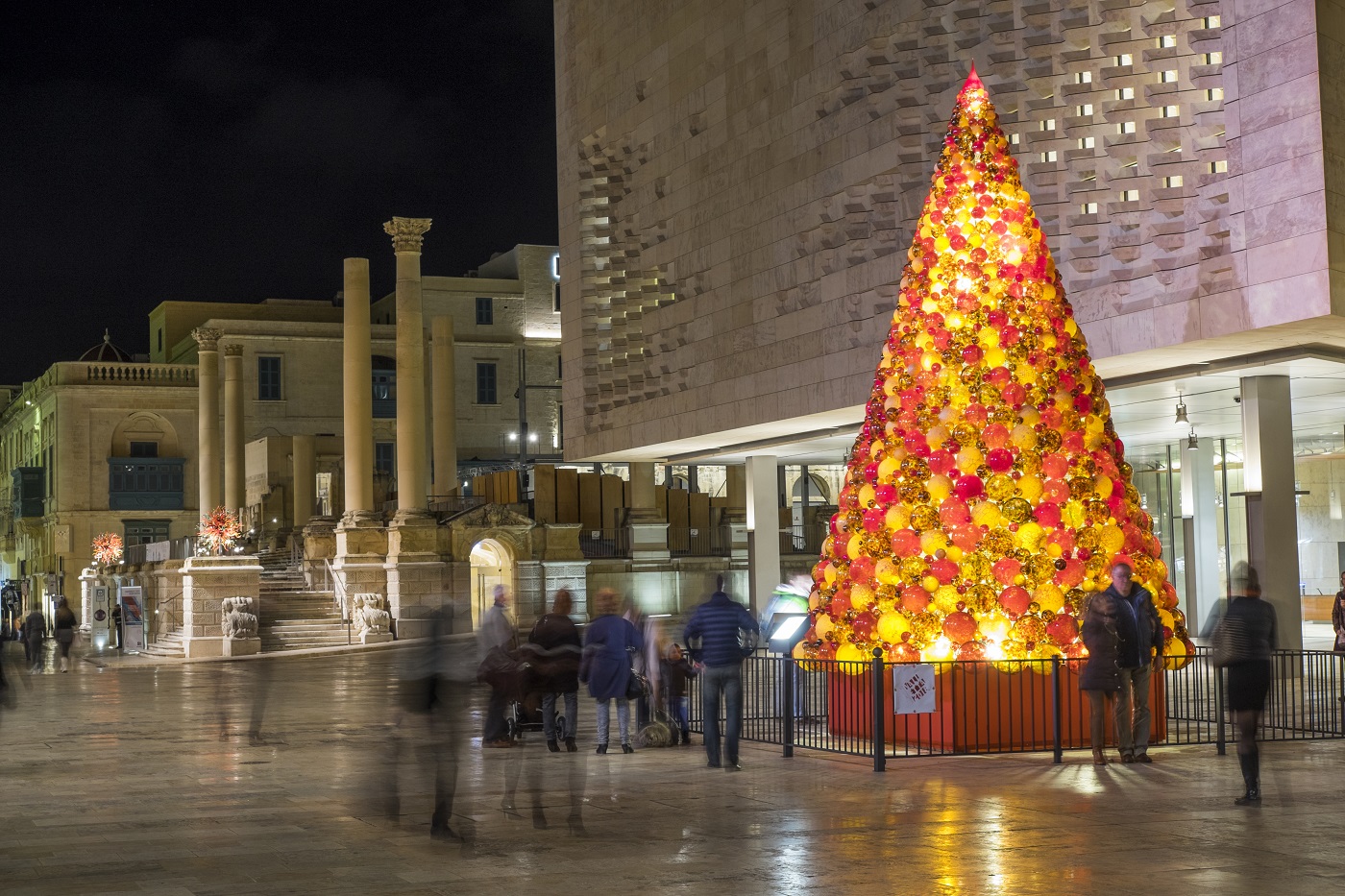 The large Christmas tree in front of Parliament building with other Christmas installation (also by Mdina Glass) in background at Pjazza Teatru Rjal.